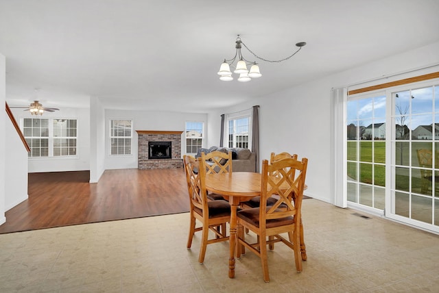 dining area featuring light floors, a brick fireplace, visible vents, and a healthy amount of sunlight