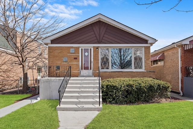 view of front of house with a front yard, brick siding, and fence