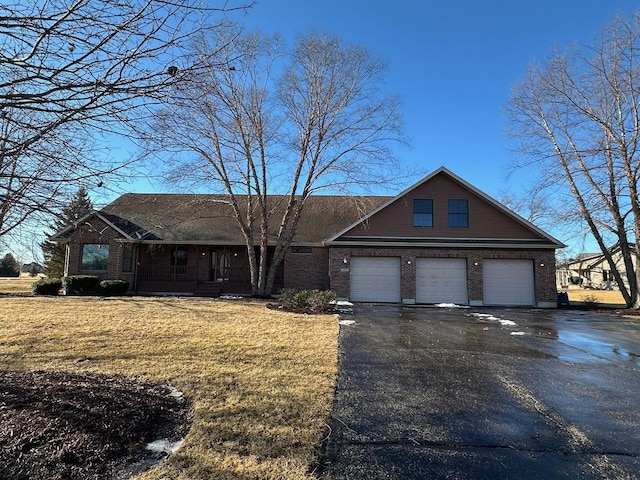 view of front facade with driveway, covered porch, a front yard, and brick siding