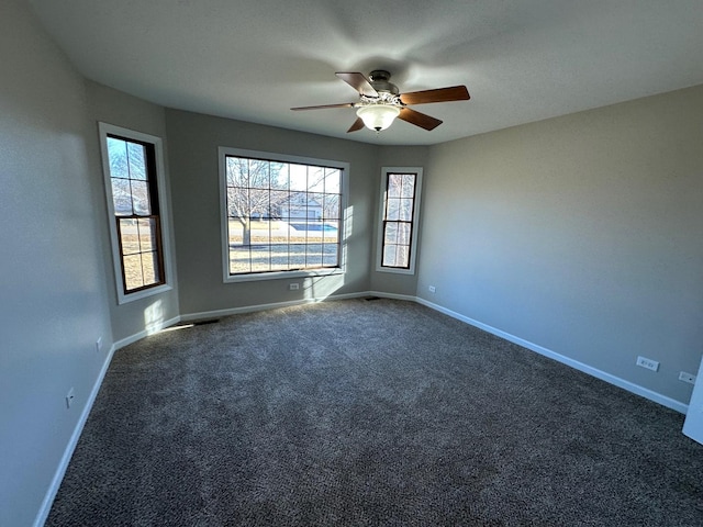 empty room featuring ceiling fan, dark carpet, and baseboards