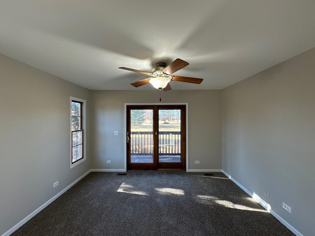 empty room featuring a ceiling fan, dark carpet, and baseboards