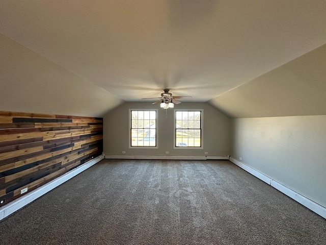 additional living space featuring lofted ceiling, ceiling fan, wood walls, baseboards, and dark carpet