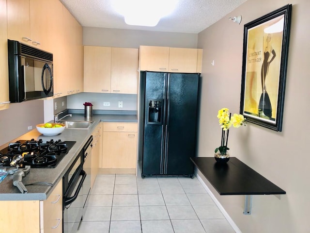 kitchen featuring light tile patterned flooring, a sink, light brown cabinetry, black appliances, and dark countertops