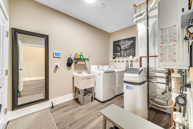 washroom featuring light wood finished floors, tankless water heater, separate washer and dryer, laundry area, and baseboards