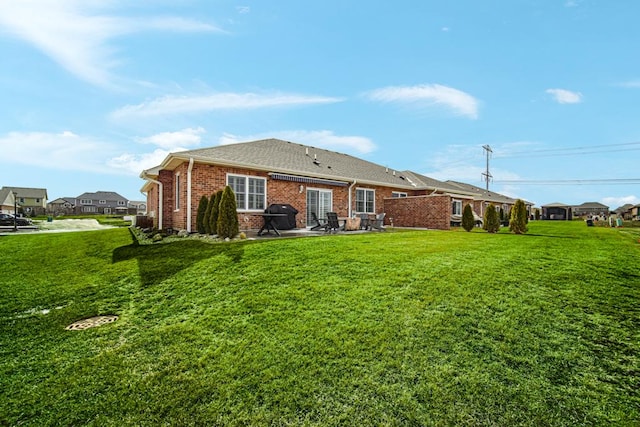 back of house featuring a yard, brick siding, a patio, and a shingled roof