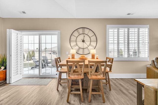 dining room with baseboards, plenty of natural light, visible vents, and wood finished floors