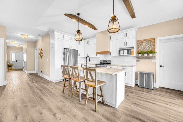 kitchen with vaulted ceiling with beams, custom range hood, appliances with stainless steel finishes, a sink, and a kitchen breakfast bar