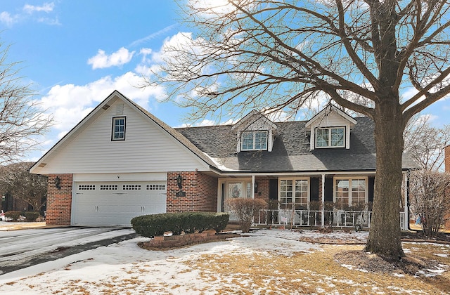 cape cod house featuring a garage, driveway, brick siding, and a shingled roof