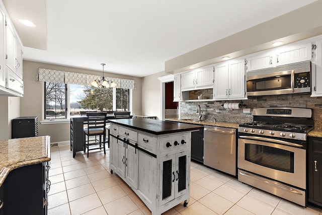 kitchen with stainless steel appliances, tasteful backsplash, white cabinetry, and light tile patterned floors