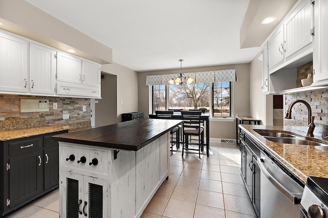 kitchen featuring light tile patterned floors, butcher block countertops, a sink, white cabinetry, and dishwasher