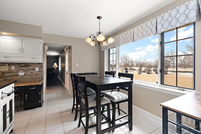 dining room featuring a notable chandelier, light tile patterned flooring, and baseboards