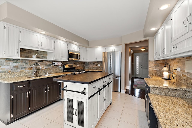 kitchen with appliances with stainless steel finishes, white cabinets, and a sink