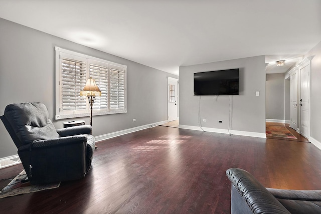 living area with wood finished floors, visible vents, and baseboards