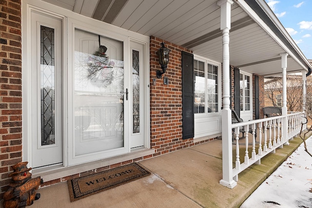 entrance to property with brick siding and a porch