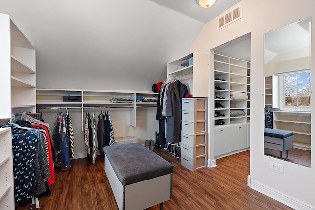 spacious closet with lofted ceiling, visible vents, and wood finished floors