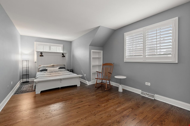 bedroom with dark wood-style floors, baseboards, visible vents, and vaulted ceiling