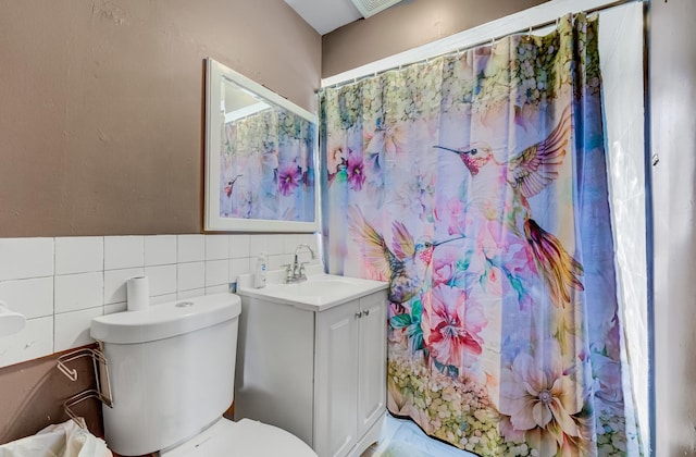 bathroom featuring tile walls, curtained shower, vanity, and toilet