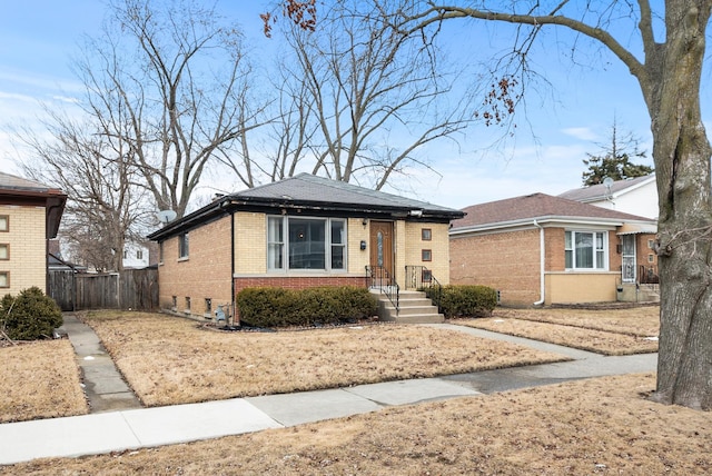 bungalow-style home with fence and brick siding