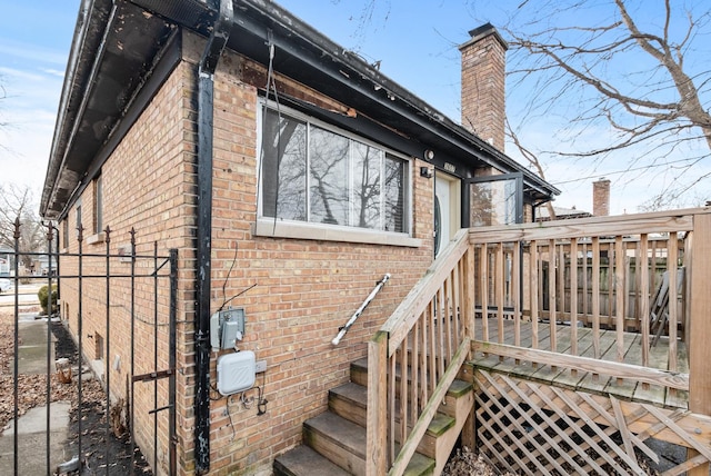 exterior space featuring a chimney, fence, a deck, and brick siding