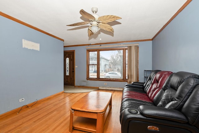 living area with ceiling fan, a baseboard heating unit, wood finished floors, baseboards, and ornamental molding