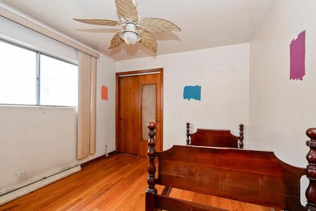 bedroom with baseboard heating, a ceiling fan, and light wood-style floors