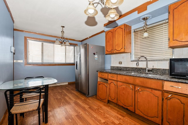 kitchen featuring a sink, stainless steel refrigerator with ice dispenser, light wood finished floors, brown cabinetry, and pendant lighting