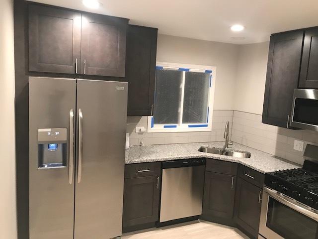 kitchen featuring tasteful backsplash, appliances with stainless steel finishes, light wood-style floors, a sink, and light stone countertops