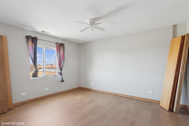 spare room with visible vents, light wood-style flooring, baseboards, and a ceiling fan