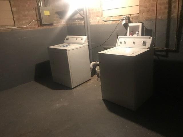 clothes washing area with laundry area, electric panel, and washer and clothes dryer