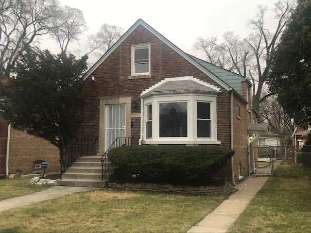 bungalow with a front yard, a gate, brick siding, and fence