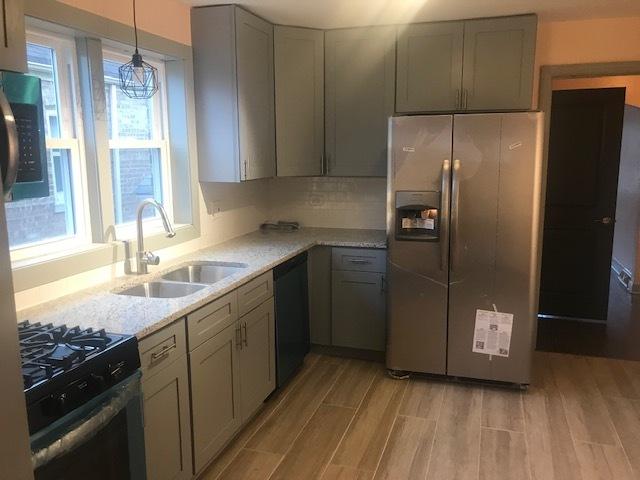 10939 S Normal Ave, Chicago, IL 60628 - kitchen featuring appliances with stainless steel finishes, a sink, light wood finished floors, and gray cabinetry