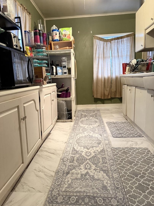 kitchen with black microwave, marble finish floor, white cabinets, and crown molding