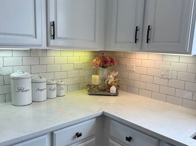 kitchen featuring tasteful backsplash, white cabinetry, and light stone countertops