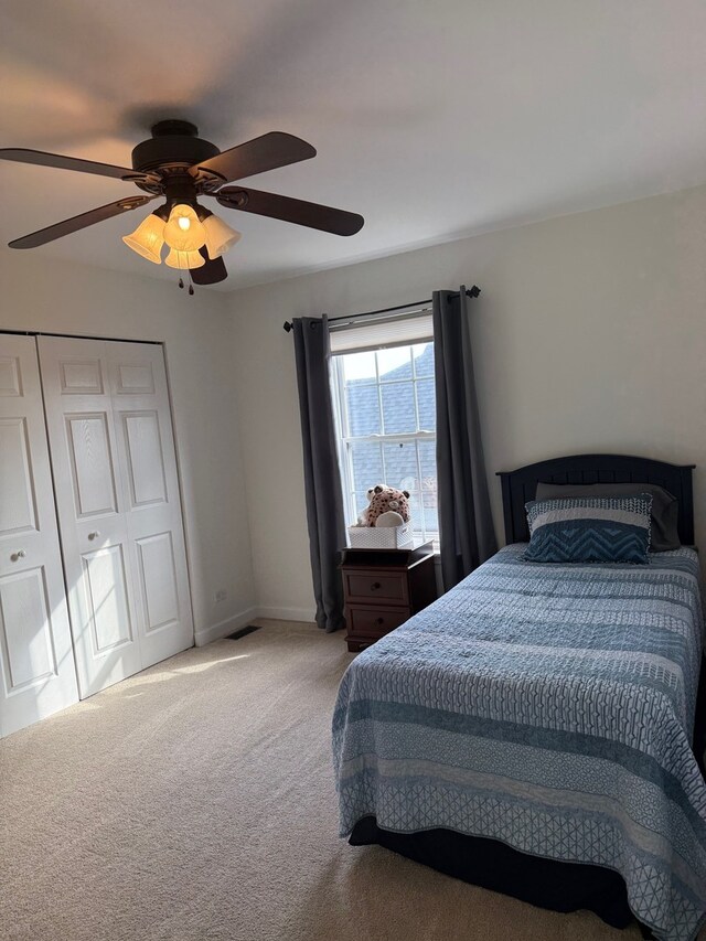 bedroom featuring ceiling fan, light carpet, visible vents, baseboards, and a closet