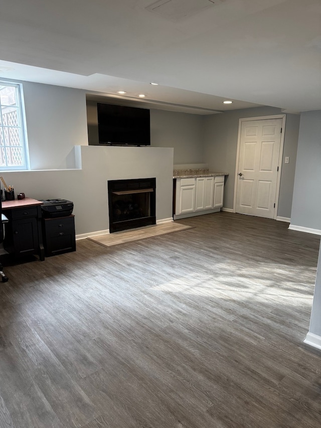 unfurnished living room with a fireplace with flush hearth, baseboards, wood finished floors, and recessed lighting