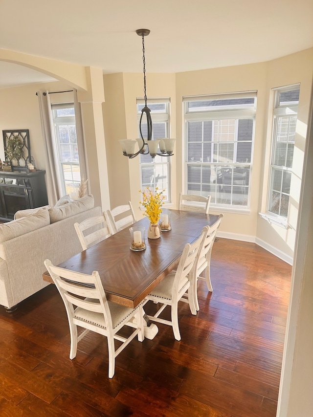 dining room featuring an inviting chandelier, wood-type flooring, baseboards, and arched walkways