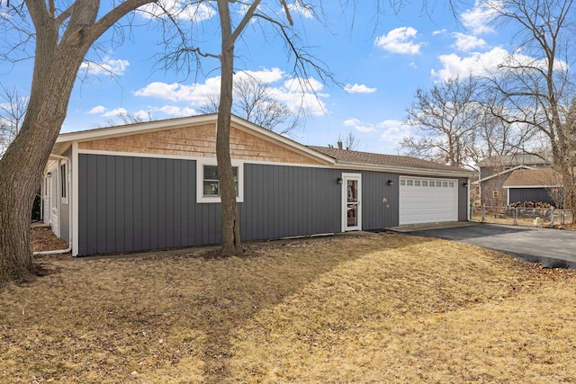 view of front of property with aphalt driveway, fence, and a garage