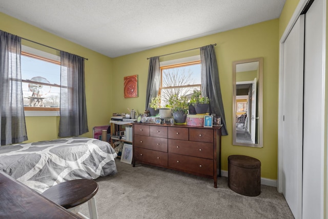 bedroom with a textured ceiling, a closet, baseboards, and light colored carpet