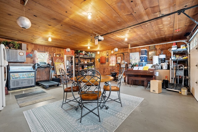 dining room featuring concrete flooring, wooden ceiling, and wood walls