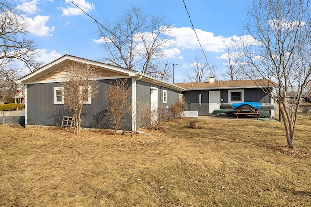 rear view of property featuring a garage, a lawn, and a chimney