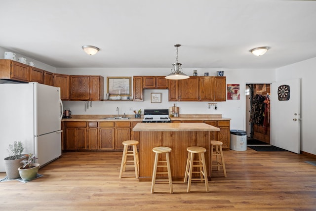 kitchen with white appliances, light countertops, a sink, and light wood finished floors