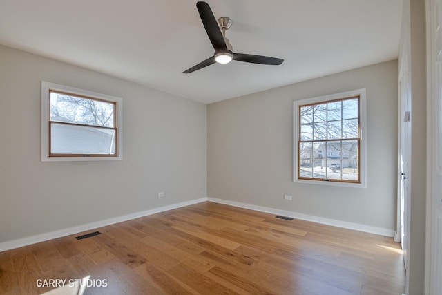 unfurnished room featuring baseboards, light wood-style floors, visible vents, and a healthy amount of sunlight