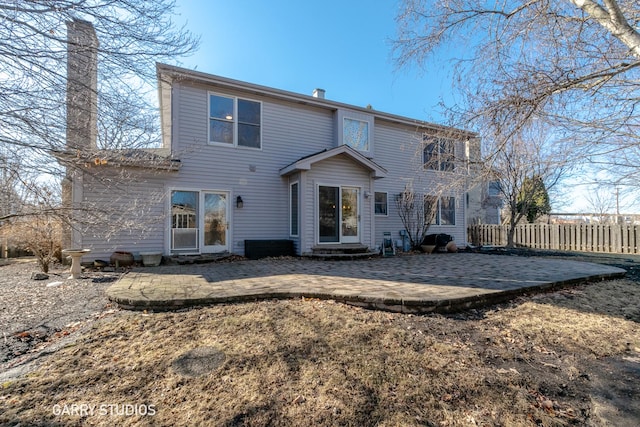 rear view of property featuring entry steps, a chimney, fence, and a patio