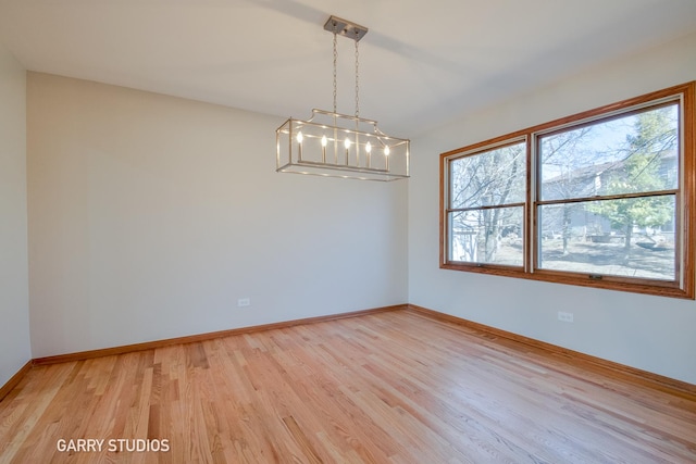 spare room featuring baseboards and light wood-style floors