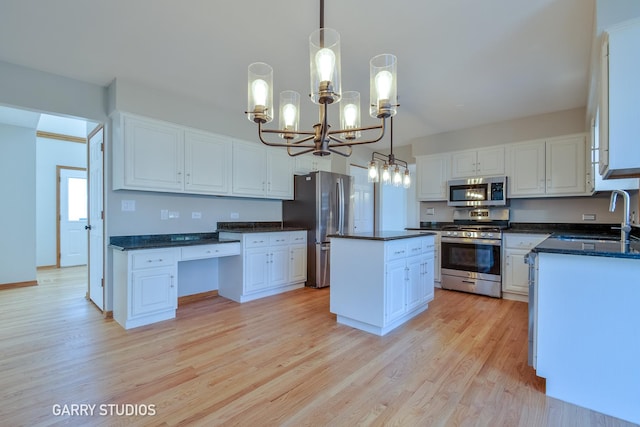 kitchen featuring light wood finished floors, a chandelier, stainless steel appliances, and a sink