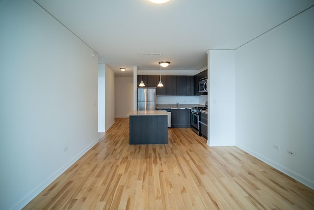 kitchen featuring light wood finished floors, a kitchen island, appliances with stainless steel finishes, and light countertops