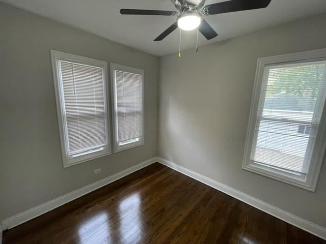 empty room with ceiling fan, baseboards, and dark wood-type flooring