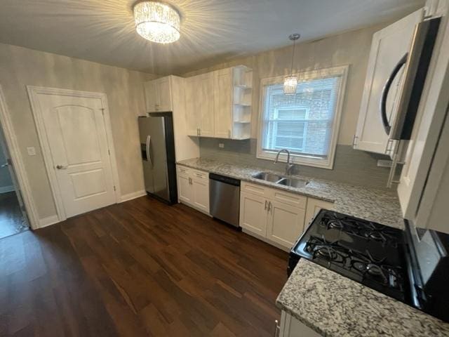 kitchen featuring light stone counters, stainless steel appliances, dark wood-type flooring, white cabinets, and a sink