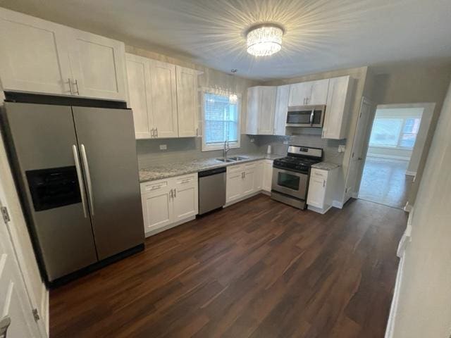 kitchen featuring white cabinetry, appliances with stainless steel finishes, dark wood finished floors, and a sink