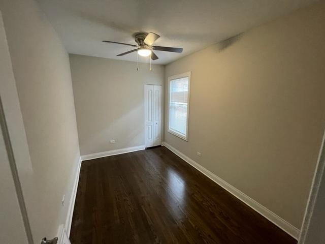 unfurnished room featuring dark wood finished floors, baseboards, and ceiling fan